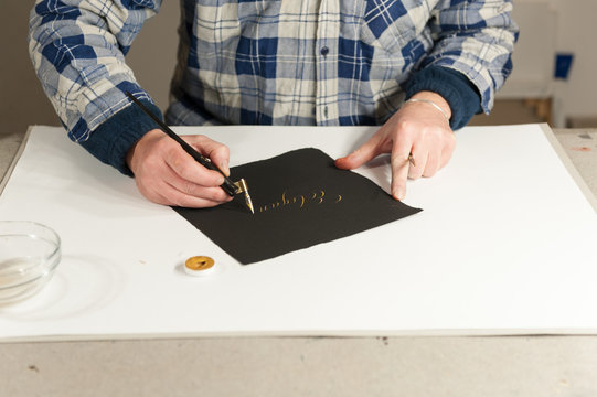 A Master Calligrapher writing elegant cursive lettering with a nib mounted on a oblique holder