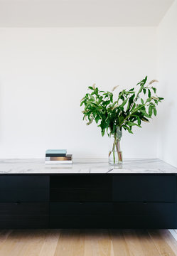 Large greenery floral display on a marble built in bench with black storage drawers