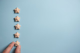 Man Hand putting wooden five star shape on blue background. Best Excellent Services Rating for Satisfaction.