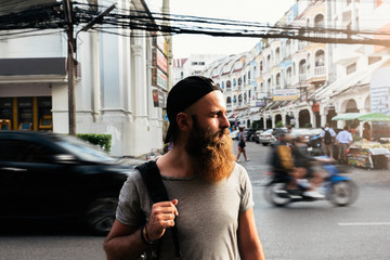 Portrait of hipster backpacker walking in the street.