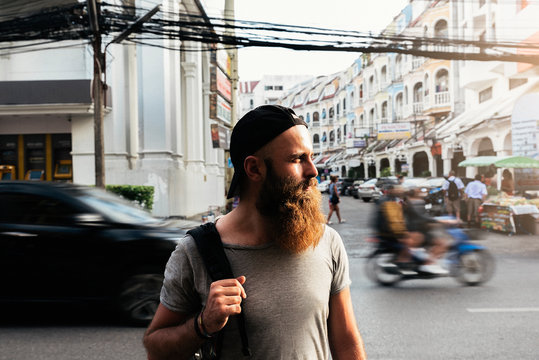 Portrait of hipster backpacker walking in the street.