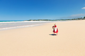 Fototapeta na wymiar Greeting card with Santa toy on beach close to sea