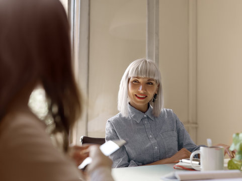 Cheerful stylish women communicating in office