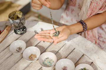 the girl is engaged in needlework from natural stones and beads