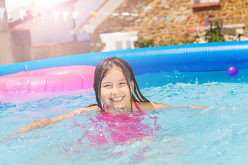 Smiling cute little girl in small swimming pool