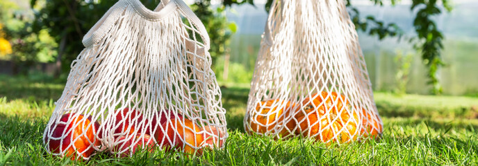 eco friendly bags of cotton with fruits and vegetables on green grass on a sunny day, levitation, zero waste concept