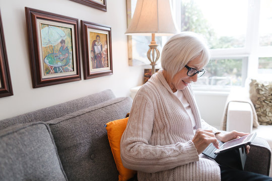 Senior woman using tablet at home on couch