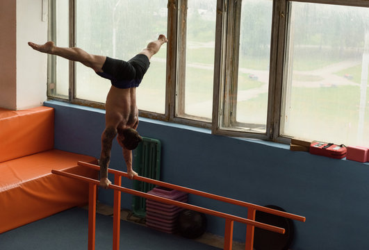 Sportsman in handstand training on bars