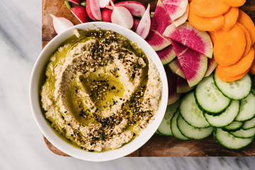Closeup photo of cauliflower hummus with Za'atar spices and sliced vegetables