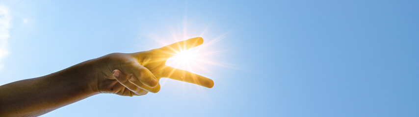 Kinderhand Victory-Zeichen / peace - Hintergrund blauer Himmel mit Sonne