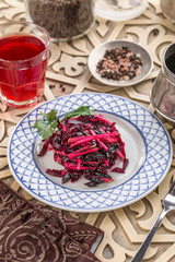 beetroot salad with apple on plate and glass of red drink on oriental wooden background