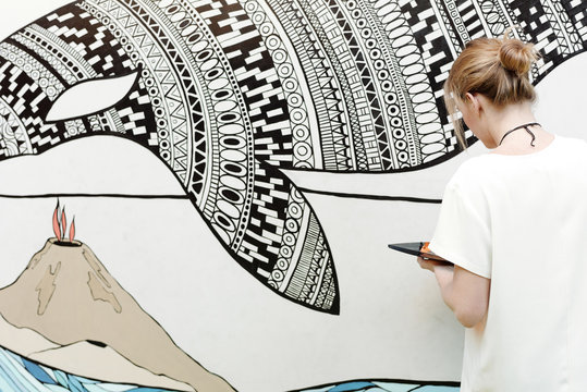 Young talented artist painting wall