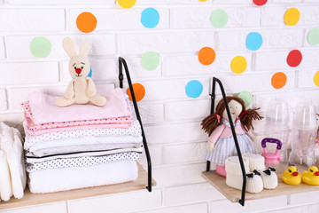 Baby accessories on shelves near white brick wall
