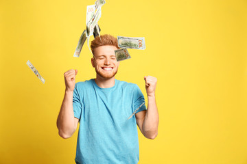 Portrait of happy lottery winner under money rain on yellow background