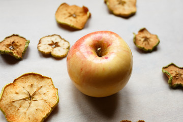Fresh apple with pieces of dry apples on the table, top view