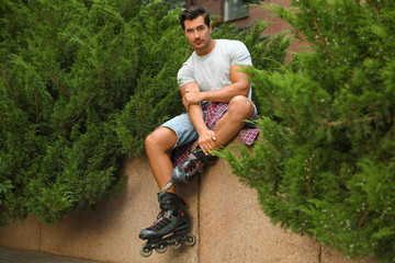 Handsome young man with roller skates outdoors