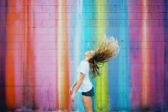 teenager girl against brightly colored walls wearing sunglasses on film