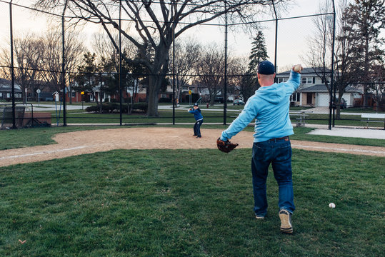 Father and son practicing baseball on a field