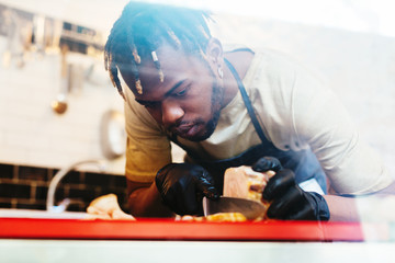 Employee cutting porchetta in a grocery store.