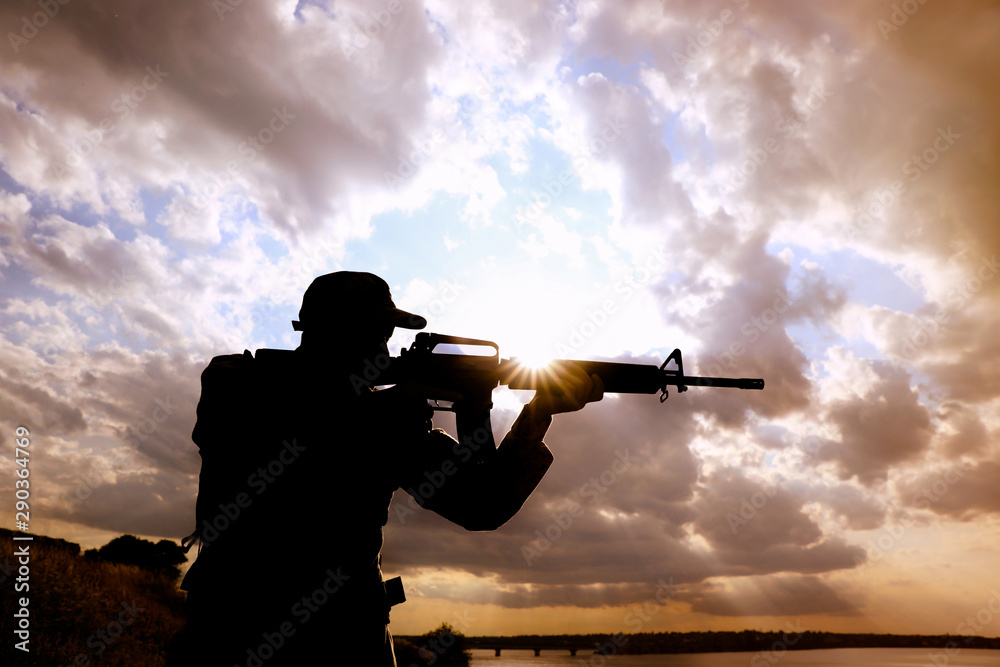 Wall mural soldier with machine gun patrolling outdoors. military service