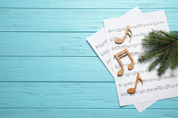 Christmas tree branch, notes and music sheets on blue wooden table, flat lay with space for text