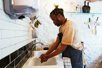 Employee working in a grocery store. Man washing hands.