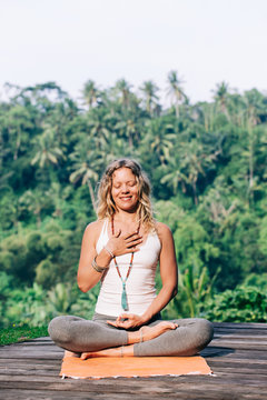 Young Blond Woman Practicing Yoga Heart Meditation in Warm Early