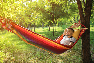 Young man resting in comfortable hammock at green garden