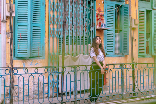Young asian woman standing on balcony of the old vintage house.