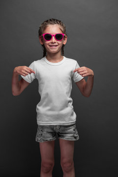 Kid girl wearing white t-shirt with space for your logo or design over gray background