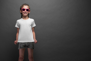 Obraz premium Kid girl wearing white t-shirt with space for your logo or design over gray background