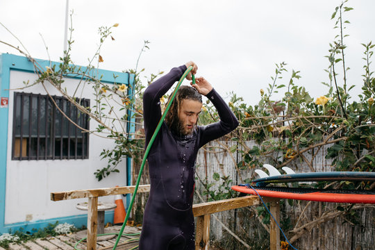 Man in swimsuit washing with hose