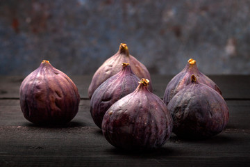 Fresh figs lie on a black wooden table. Beautiful blue fig fruits close up