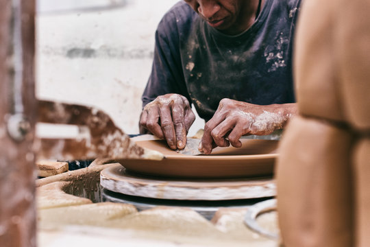 Closeup of Artisan Master Potter Scraping Plate on Flywheel