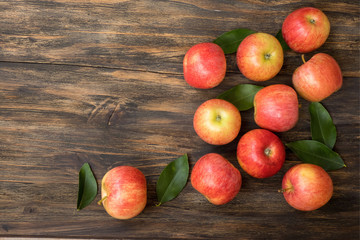 Red and pink apples with  green leaves on wooden table , close up from above , copy space