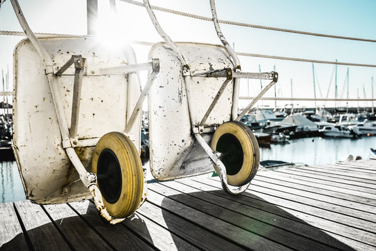 Two wheelbarrows leaning against a fence in a harbour environment