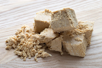 Halvah on a wooden table. Arabian sweetness of caramel mass and ground roasted kernels of nuts, peanuts, close-up.