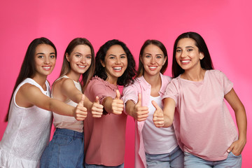 Happy women showing thumbs up on pink background. Girl power concept