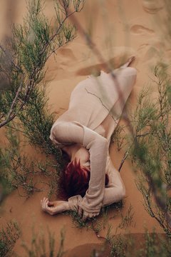 Redhead young woman daydreaming in desert