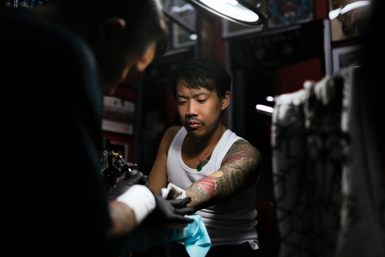 Professional asian tattooer makes a tattoo.