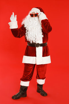 Authentic Santa Claus wearing sunglasses on red background