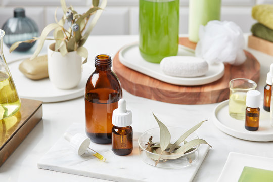 Essential oils with dried herbs or flowers on marble board.