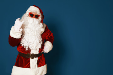 Authentic Santa Claus wearing sunglasses on blue background. Space for text