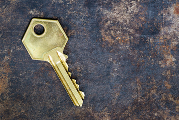Golden house door key on a rusty metal background
