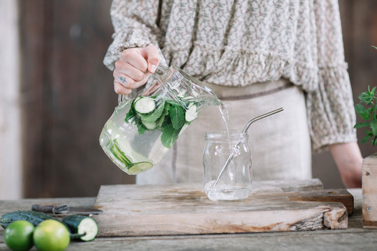 Crop woman pouring drink into jar