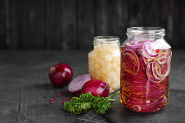 Jars of pickled onions on grey table. Space for text