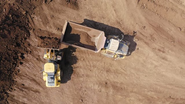 Excavator loading soil onto an Articulated hauler Truck, Top down aerial image.
