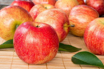Red and pink apples with  green leaves  , close up