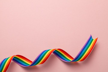 LGBT rainbow ribbon pride symbol. Pink background. Copy space for text.