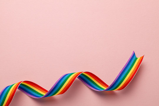 LGBT rainbow ribbon pride symbol. Pink background. Copy space for text.